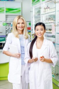 multiethnic pharmacists with digital tablet and medications smiling at camera in drugstore.jpg